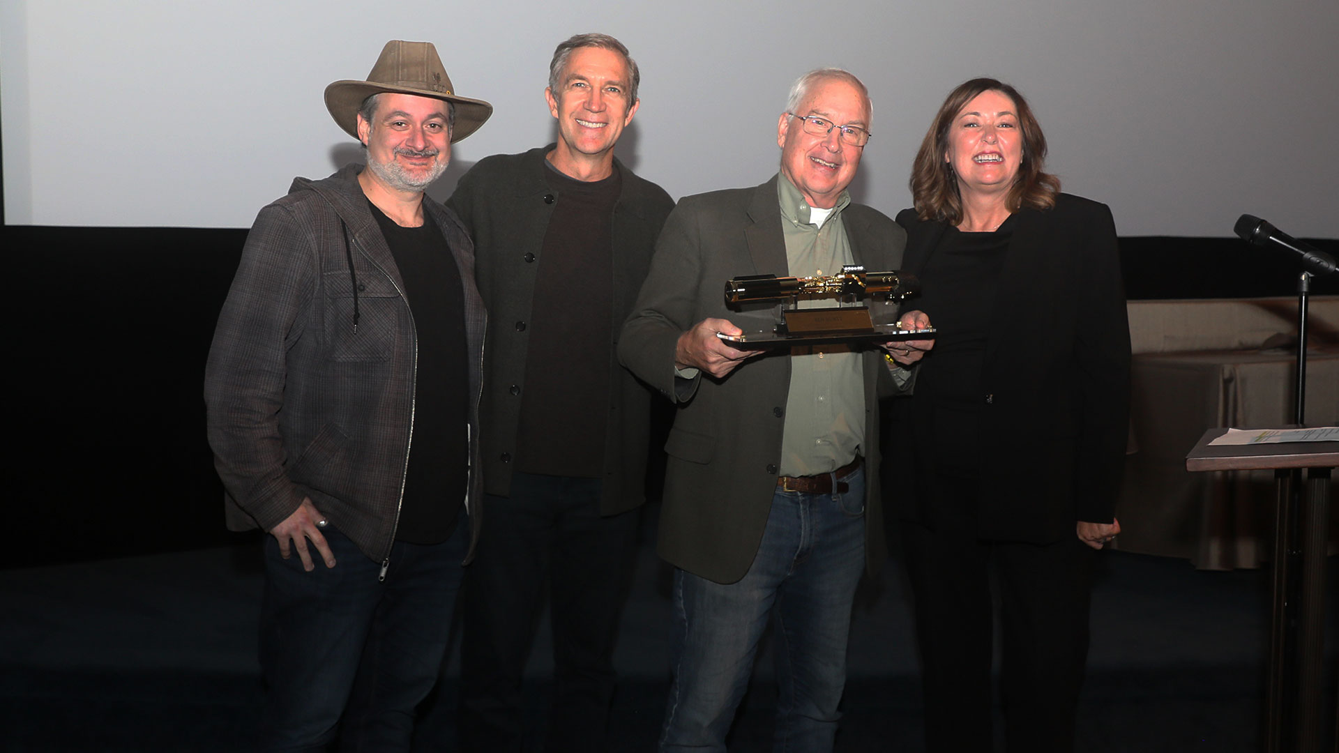 Lucasfilm's Dave Filoni, Josh Lowden, and Lynwen Brennan pose with Ben Burtt, who holds his 50th anniversary golden lightsaber.